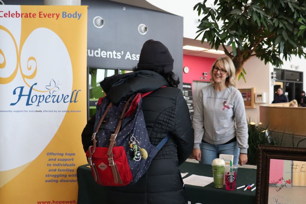 The Hopewell booth was set up in the student commons. Lindsay Dobson, a volunteer at the support centre, informs a student on their services and offers them to write a positive message on the mirror.