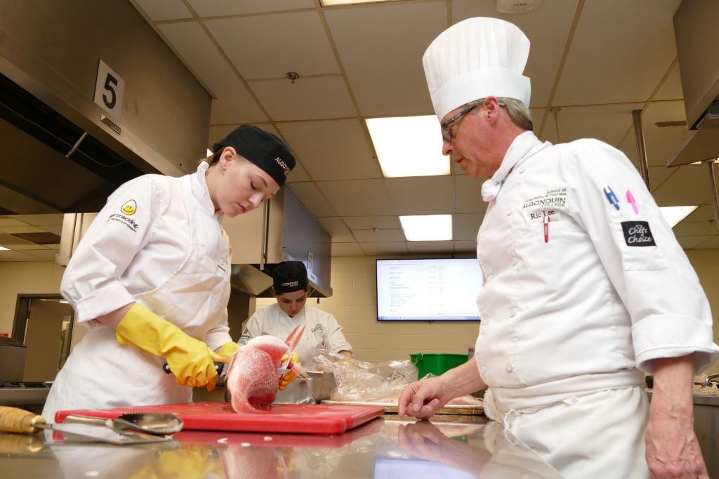 Chef Ric Lee, coach for Algonquin's culinary arts team for Skills Ontario, shows candidates Mariel Legere and Amber MacPhee how to prepare red snapper. The team will compete at the competition in Toronto from May 6 - 8.