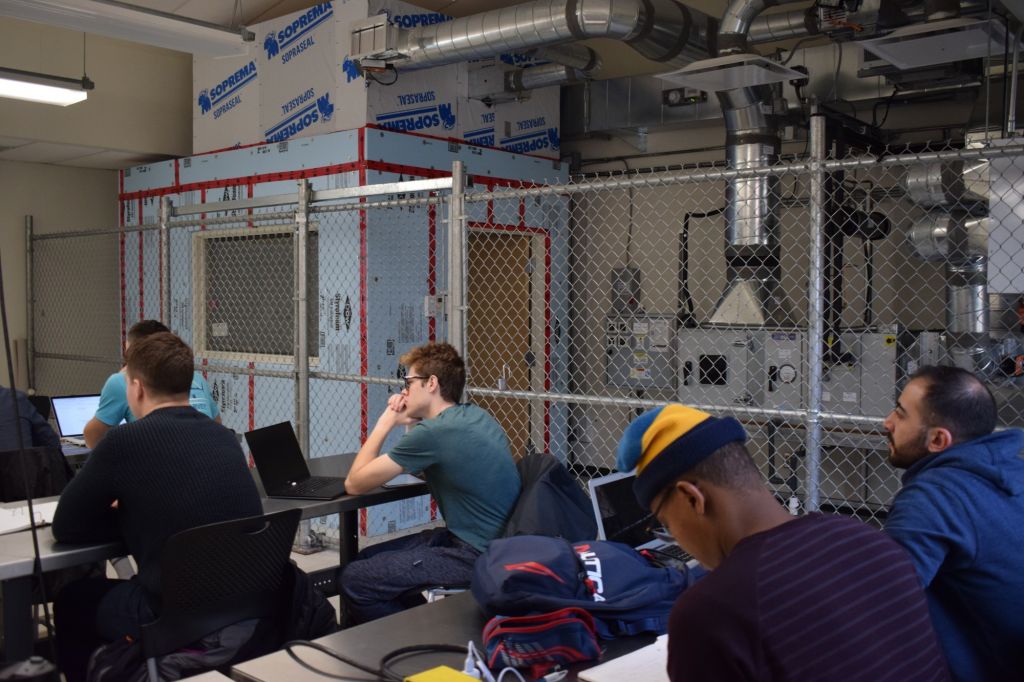 Students in class in the M-building. The self-contained shed is in the classroom, behind a fence.