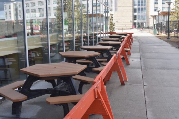 A row of picnic tables is tucked away behind orange barriers outside of E-Building on March 20.