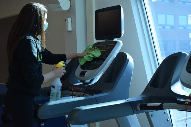Fitness and wellness coordinator Cassandra Jones St-Onge sanitizes a treadmill in the Fitness zone. The Fitness Zone reopened Sept. 8 for community members.