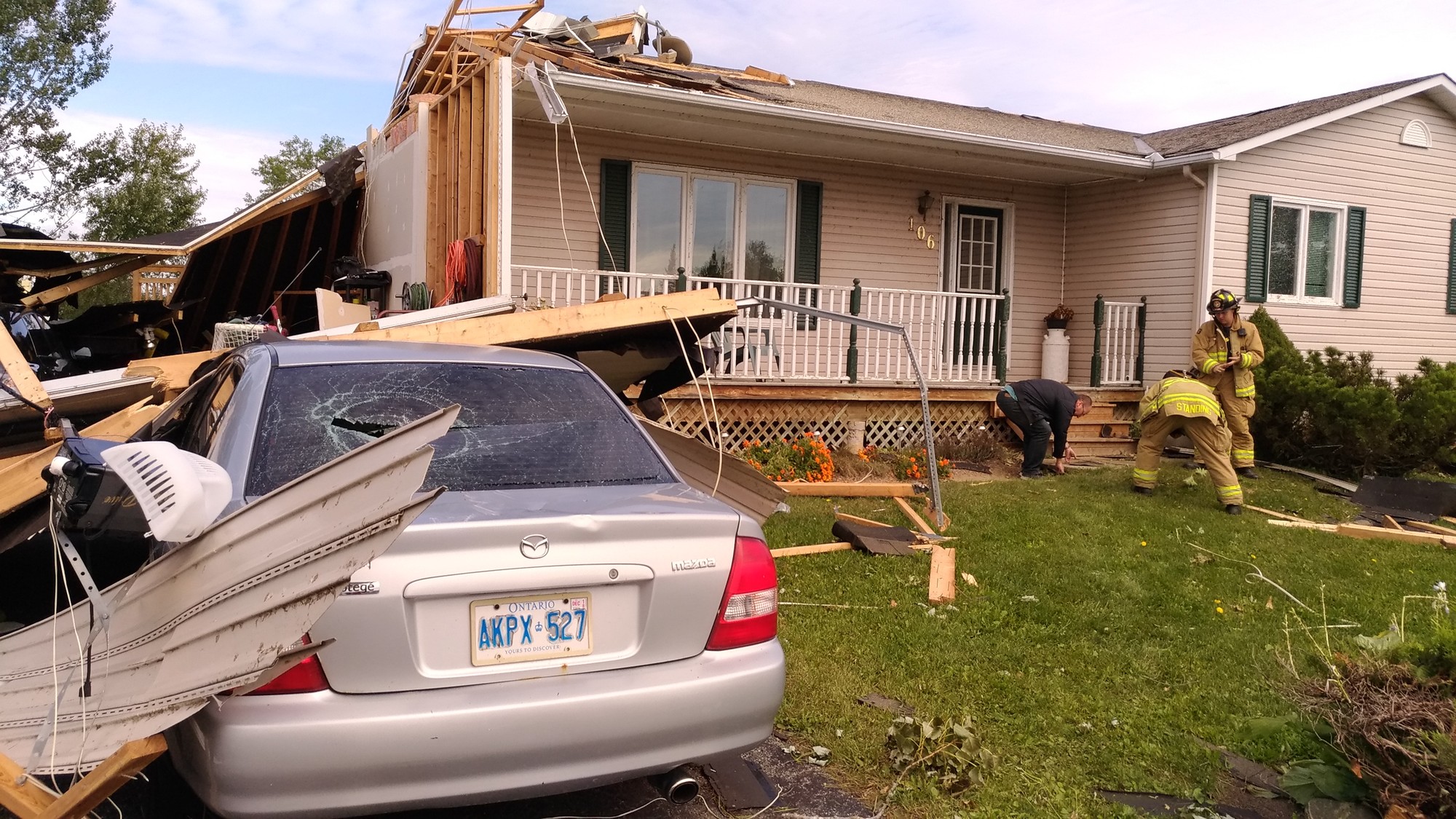 Volunteer firefighters escorting families into damaged homes to collect personal items a few days after the tornado in Dunrobin.