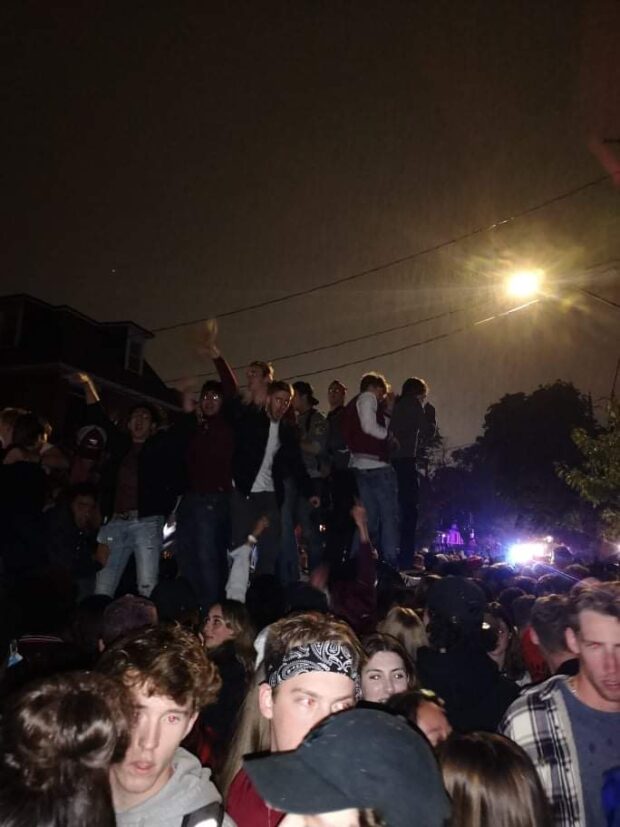 Partygoers on top of the overturned car during the street party.