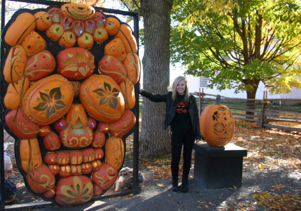 Algonquin Colege alumini Carli Smelko, Special Events Officer at Upper Canada Village, is shown with one of the creations featured in the Day of the Dead display.