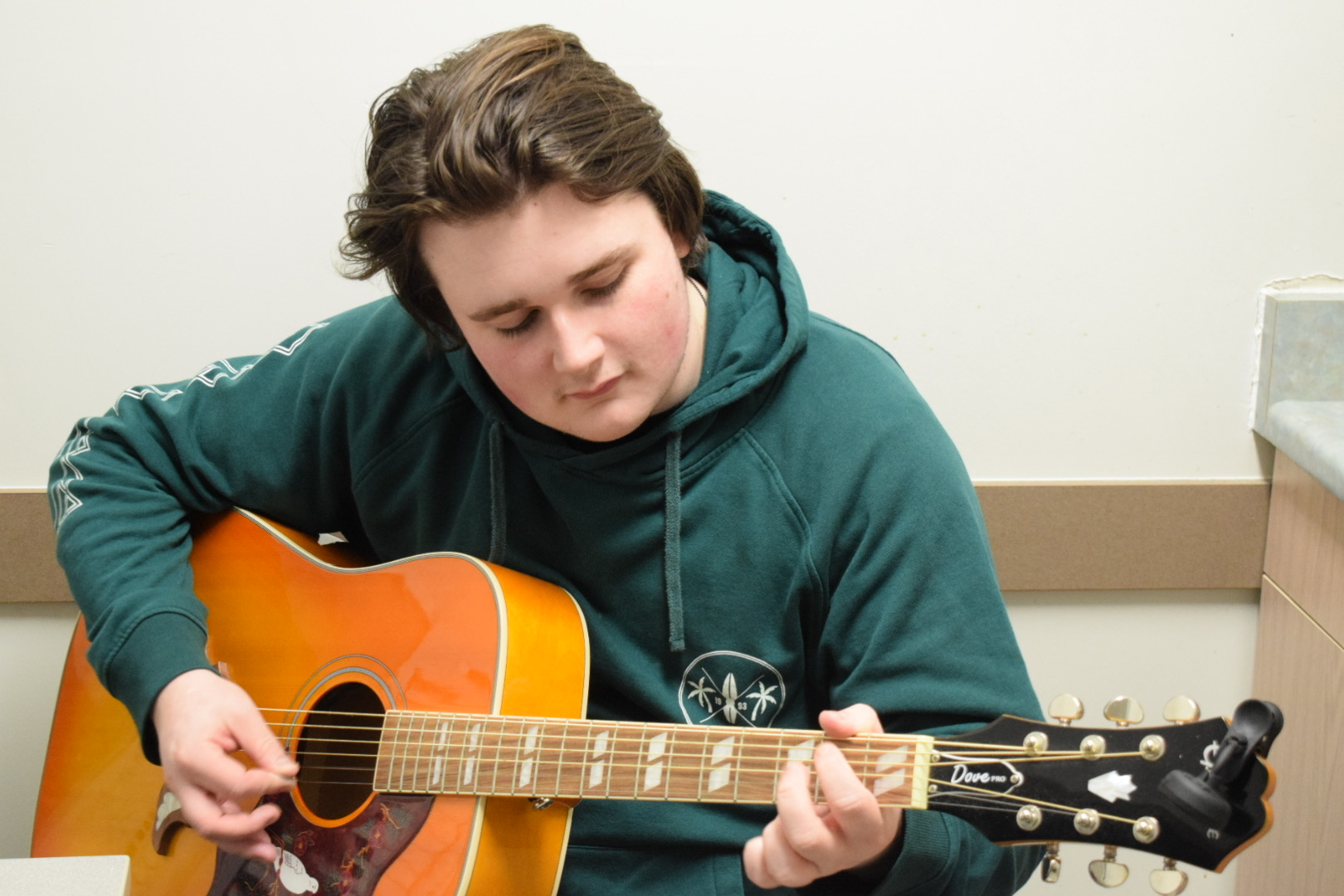 Aidan Elliot-Perreault, a music industry arts student, plays guitar in his residence room.