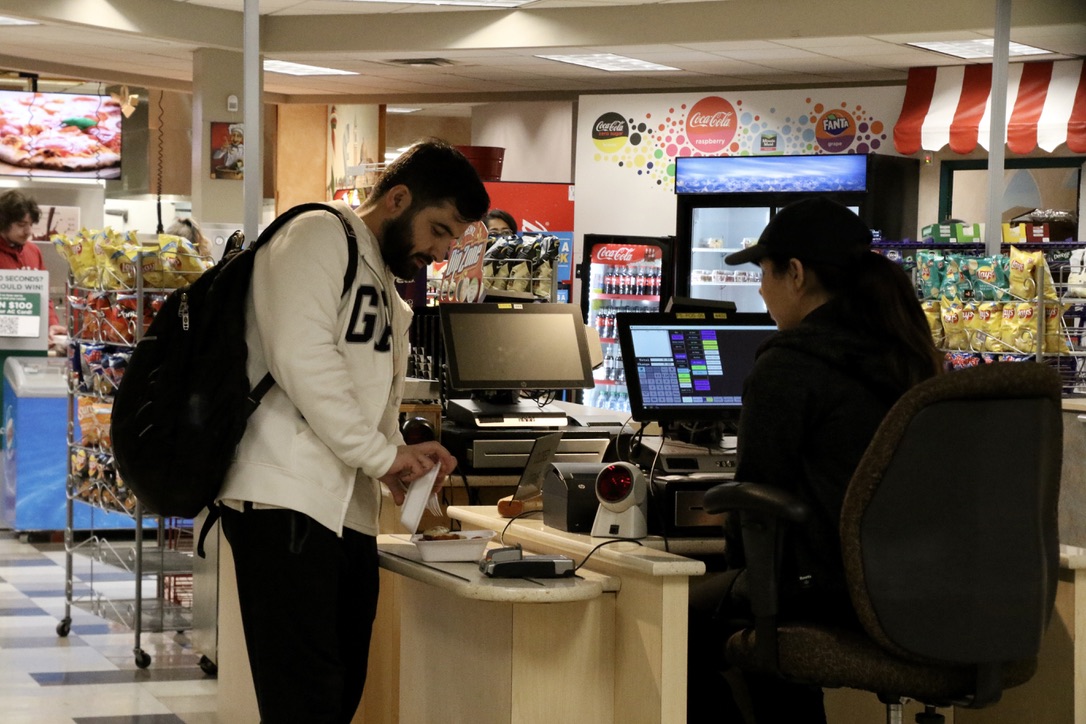 Wahwedullah Qane, a diagnostic cardiac sonography student, paying for his meal at the Marketplace Food Court at Algonquin College.