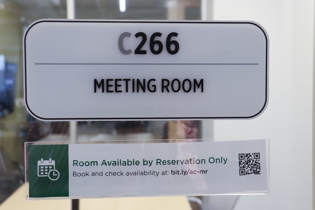 A sign with a QR code invites students to book their meeting rooms.