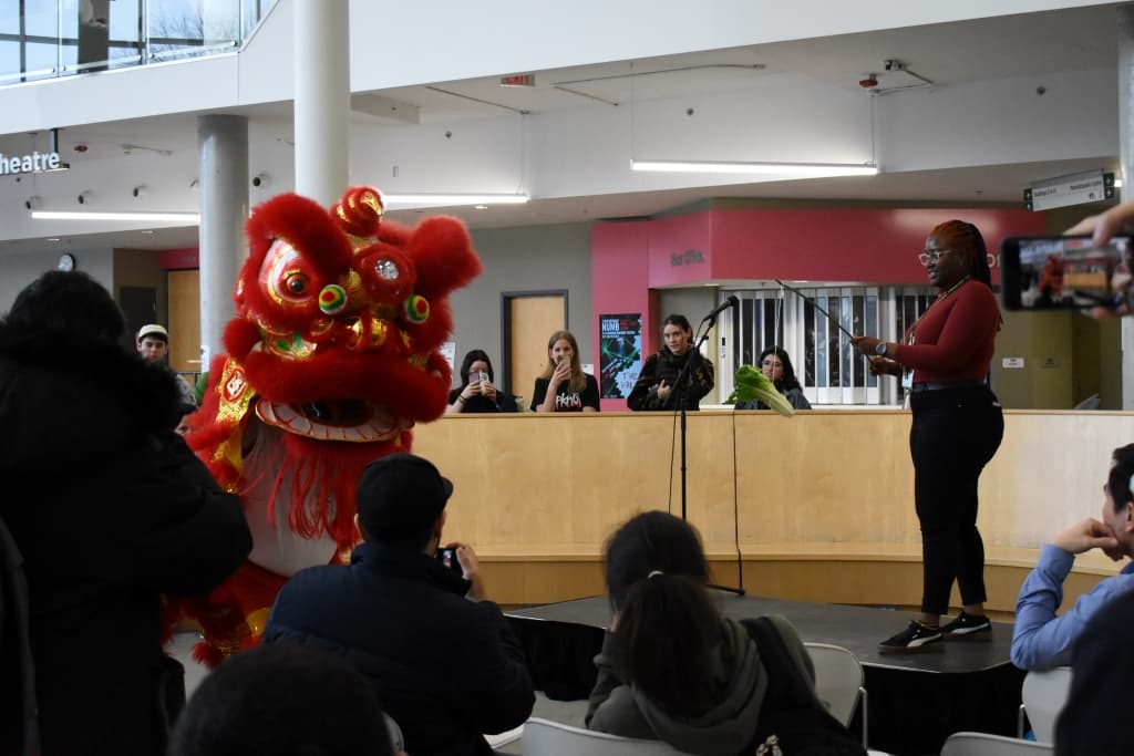 The Success Lion Dragon Dance Troupe performs at the Lunar New Year event. Nakeya Francis (right) holds out a head of lettuce for the lion as part of a Chinese lion dance tradition.