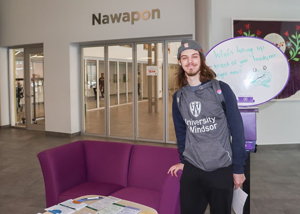 Connor Sunderland, a museum studies student, stands by the AC Purple Couch after having a talk with student health leaders.