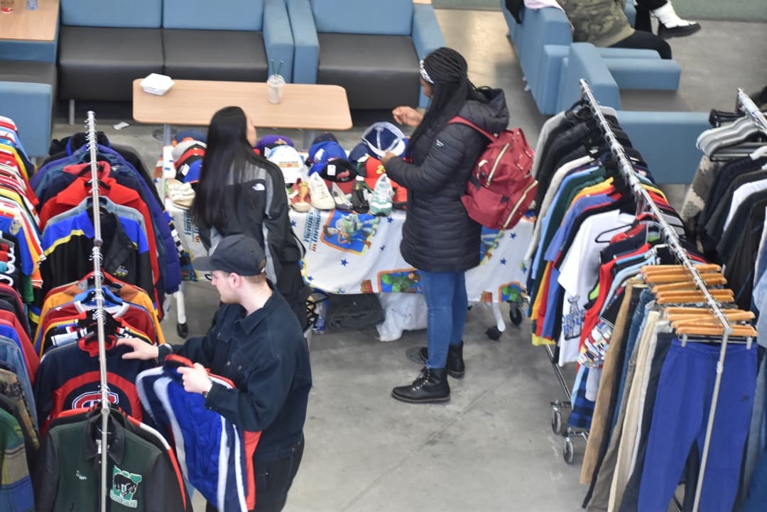 Students rummaging through clothes at vintage clothing sale.
