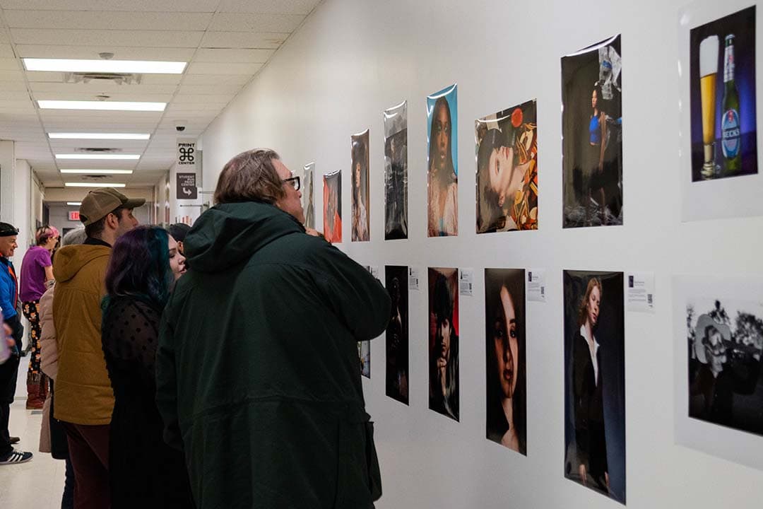 Students show their work to family and friends at the photography exhibition.