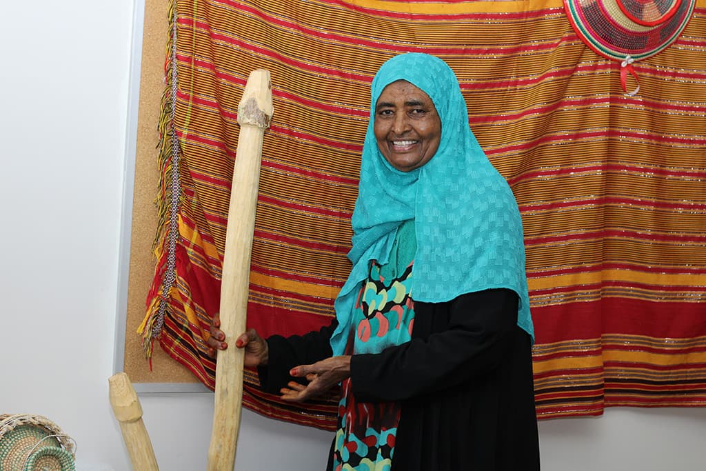 Kaltoun Moussa holding a wooden stick that Somalians use to grind the crops in the new Khayrhaye Museum. 