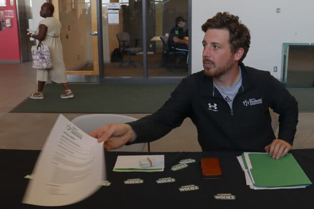Job fair volunteer Dawson Brooke hands out information for the Athletics and Recreation opportunities at Algonquin College.
