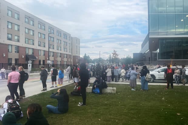 Students are seen gathered across the street after a fire alarm was pulled at the Algonquin College residence on Oct. 20, 2023.