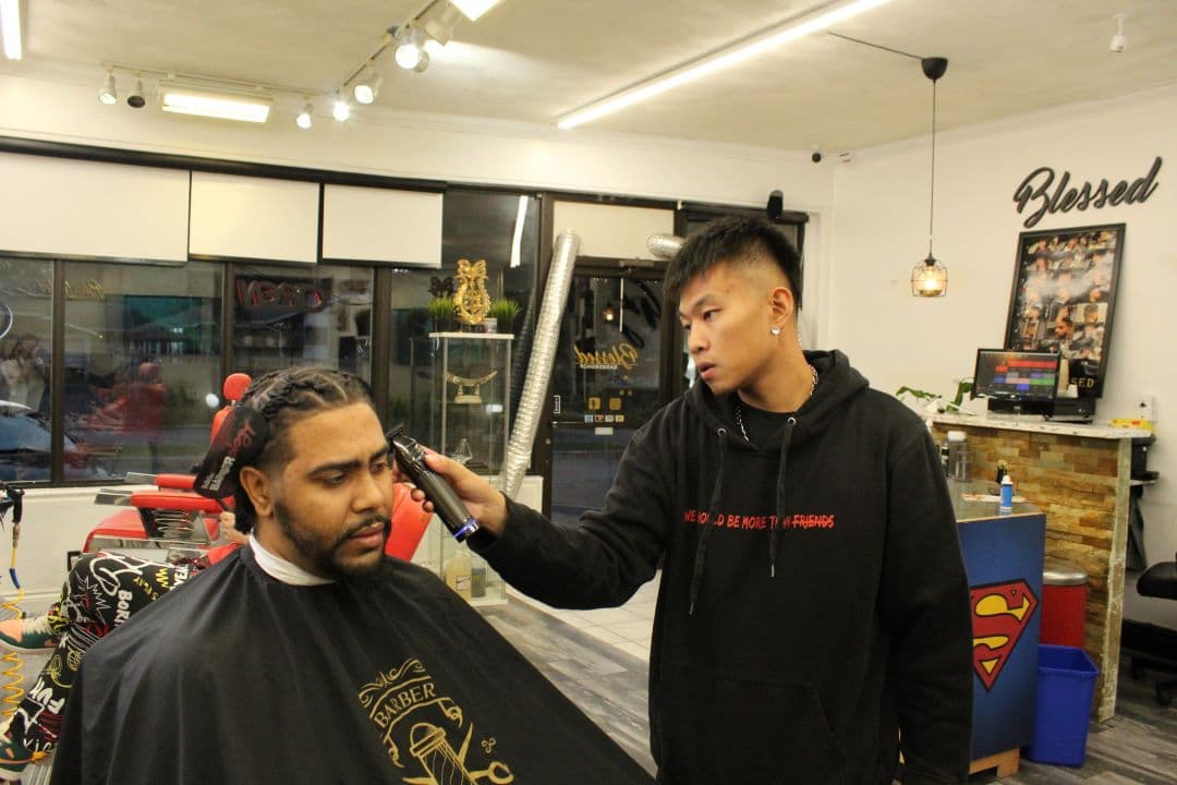 Ray Huang works on Jonathan Fletcher's hair at Blessed Barber Shop. 