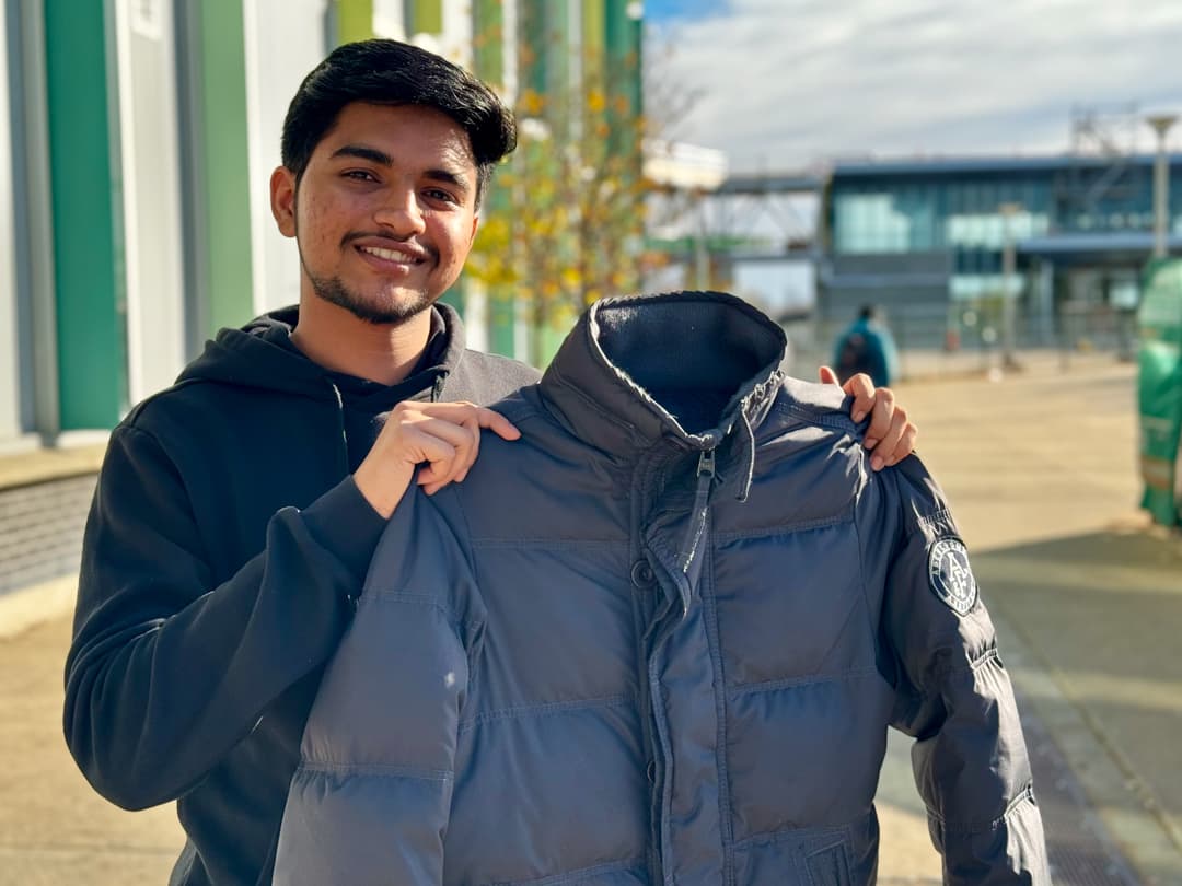 Ricky Kumar outside ACCE Building alongside the coat he brought to be donated at the event