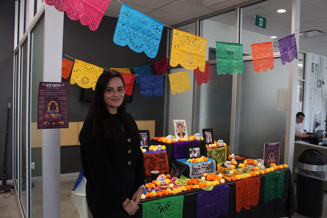 Business marketing alumna Rebeca Feria stands in front of the altar during the Day of the Dead event at the college on Nov. 2.