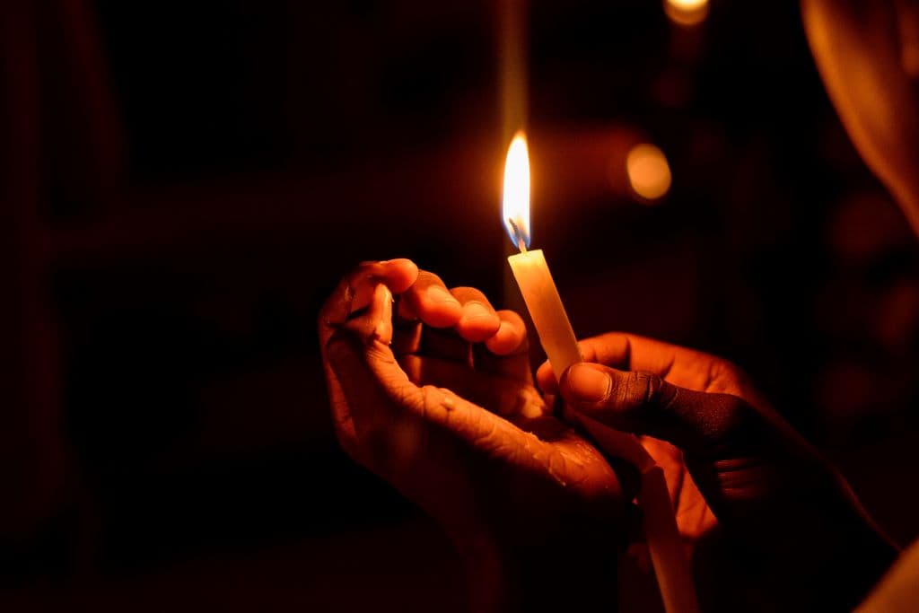 A hand holding a lit candle.