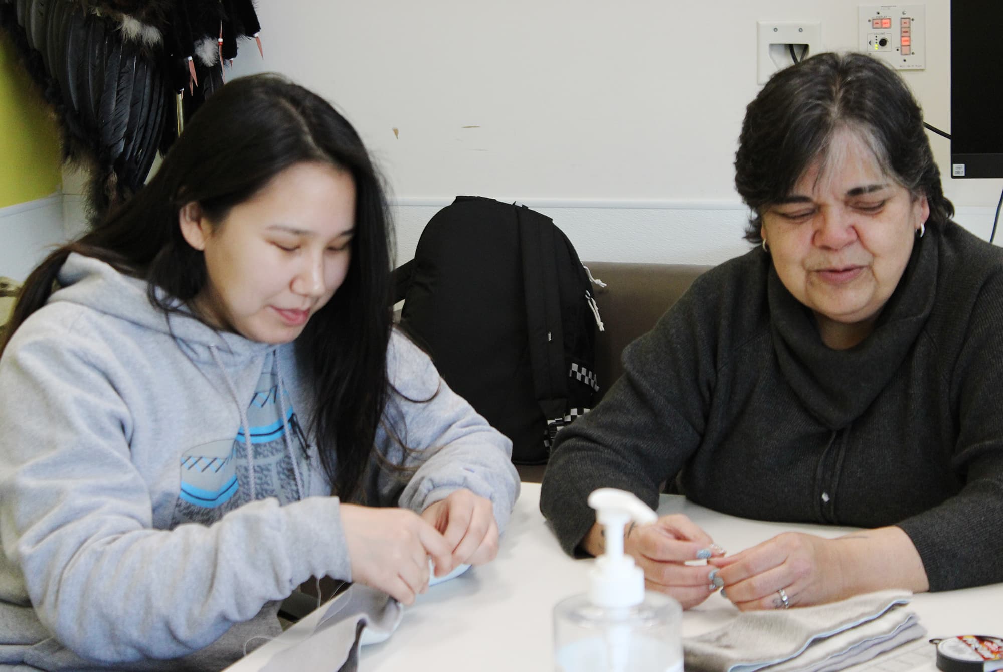 Trudy Metcalfe-Coe (right) helps a student with a seal skin headband.