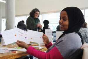 Fathi Mohamed holds up her first three kindness cards she made with the Volunteer Centre