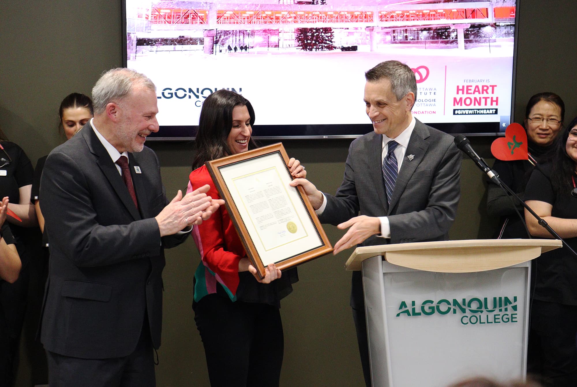 Mayor Mark Sutcliffe (right) presenting the official Heart Month proclamation to Claude Brulé (left) and Lianne Laing (middle).