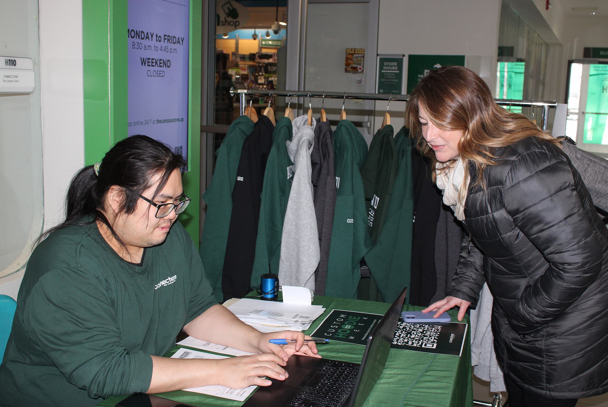 Chorn Lo, sales associate at the Connections store, takes an order for a custom hoodie from Shannon Reid, veterinary program curriculum coordinator.