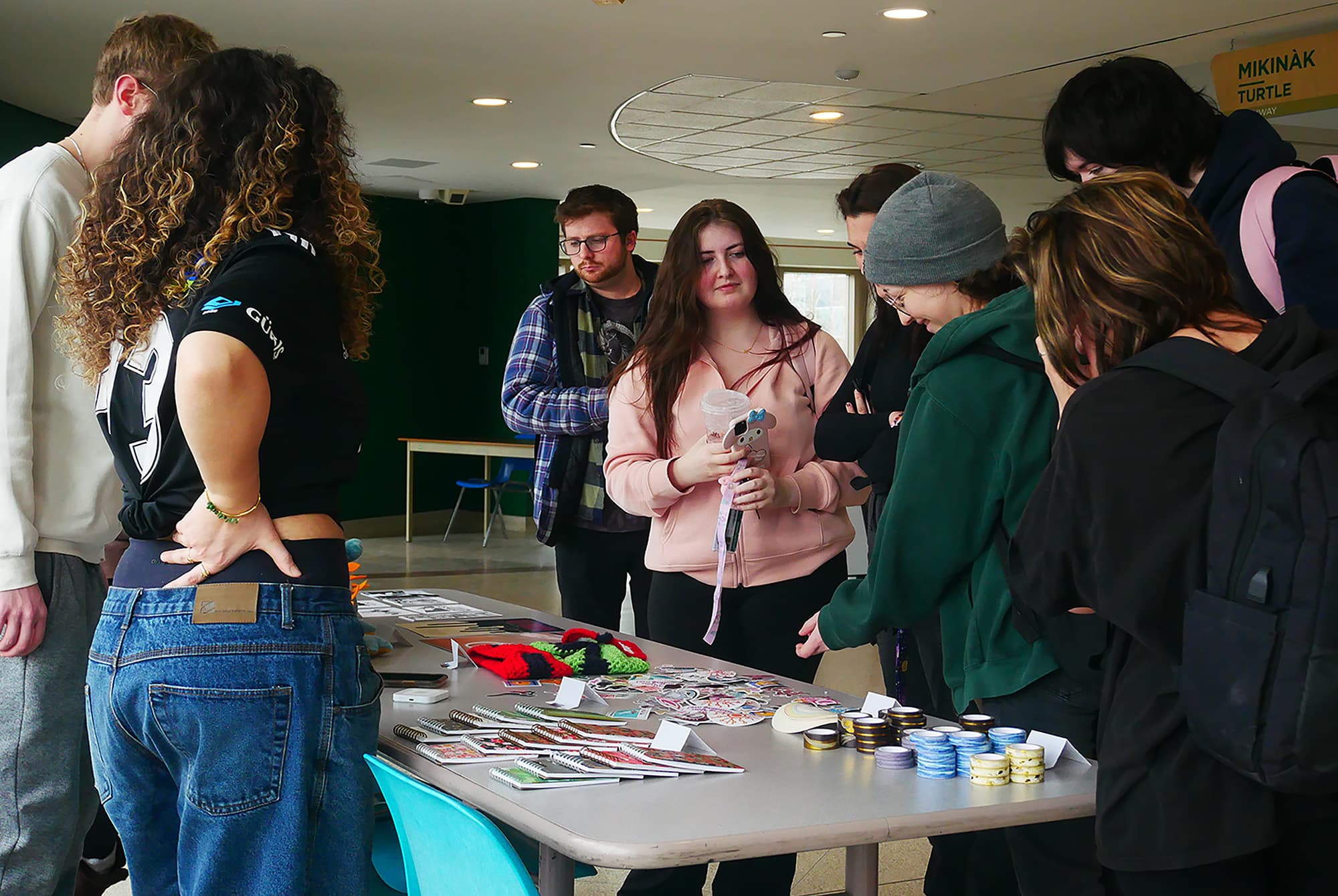Daniel Neilson (behind the table, on the left) and Enissa Ciper (behind the table, on the right), sell art to first-year graphic design students in the intersection between the N, J and B-buildings.