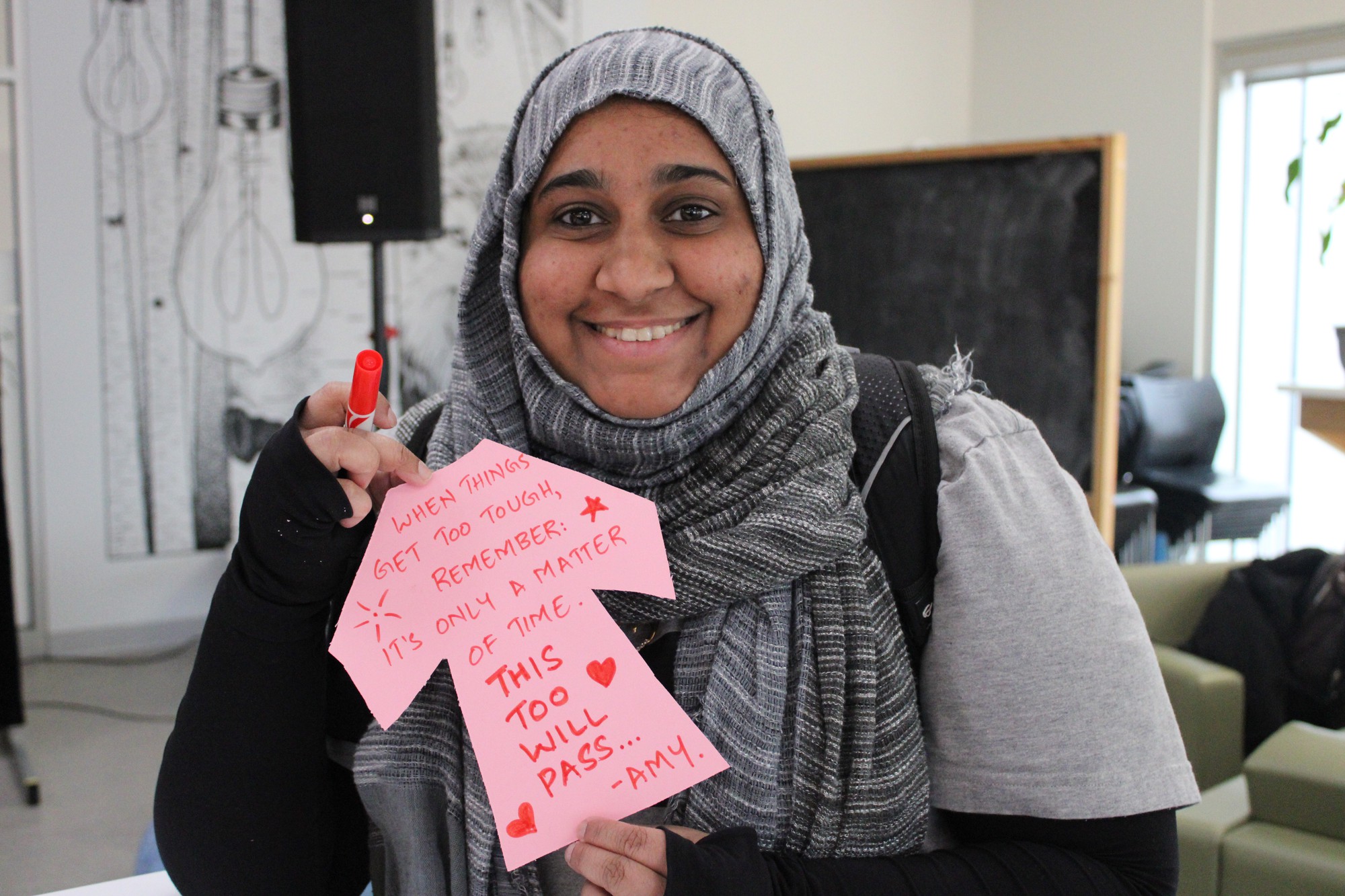 Amina Shahin, a technical writer student, shows her anti-bullying message on the little pink shirt cardstock.