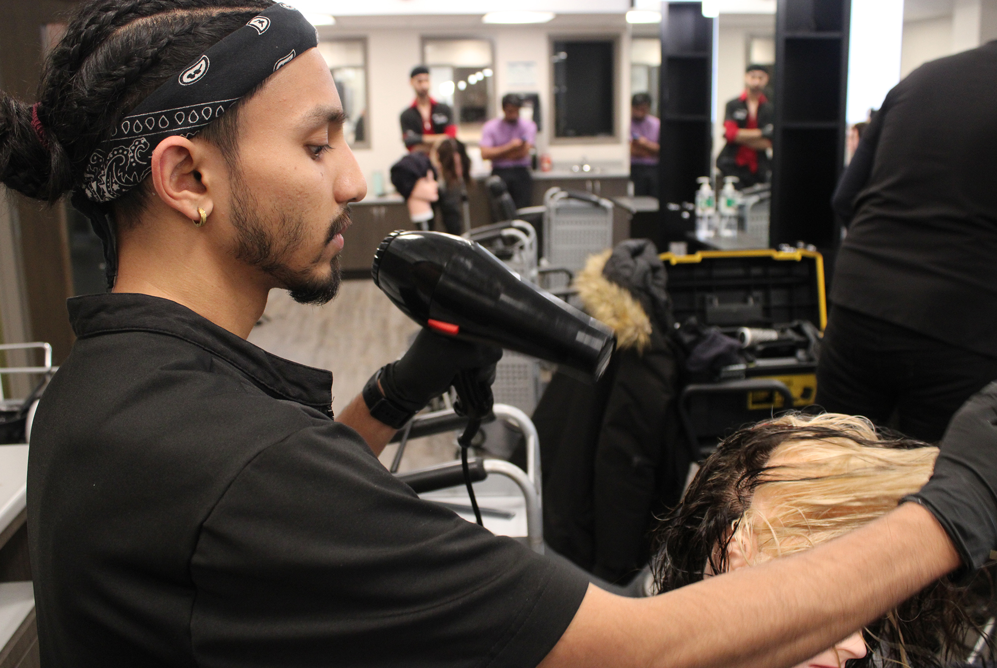 Hairstyling student Ahnaf Hassan dries a mannequin's hair before styling it at the salon in A-building on March 12.