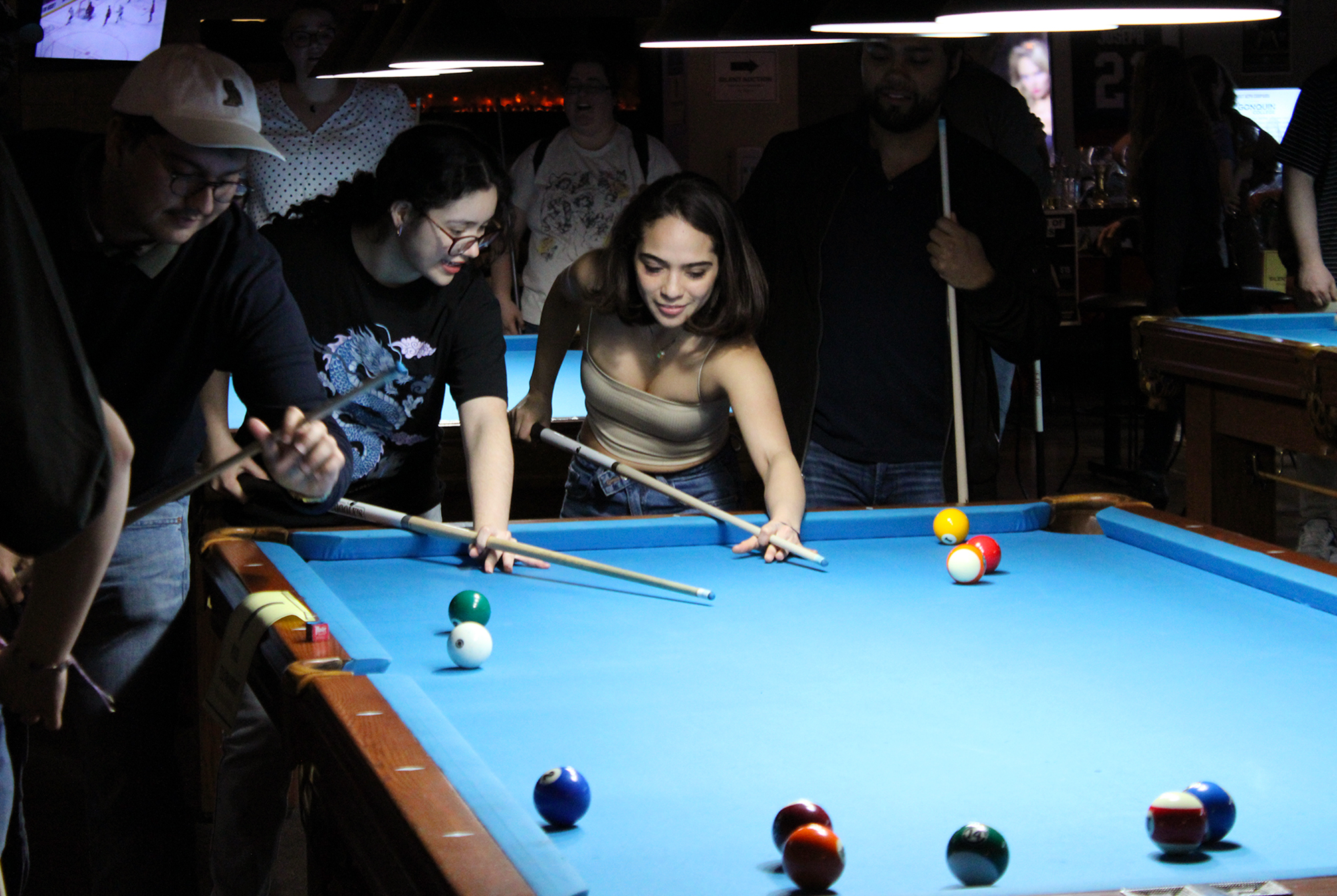 Sarah Porras, a public relations student, on the right, being taught how to hold the cue.