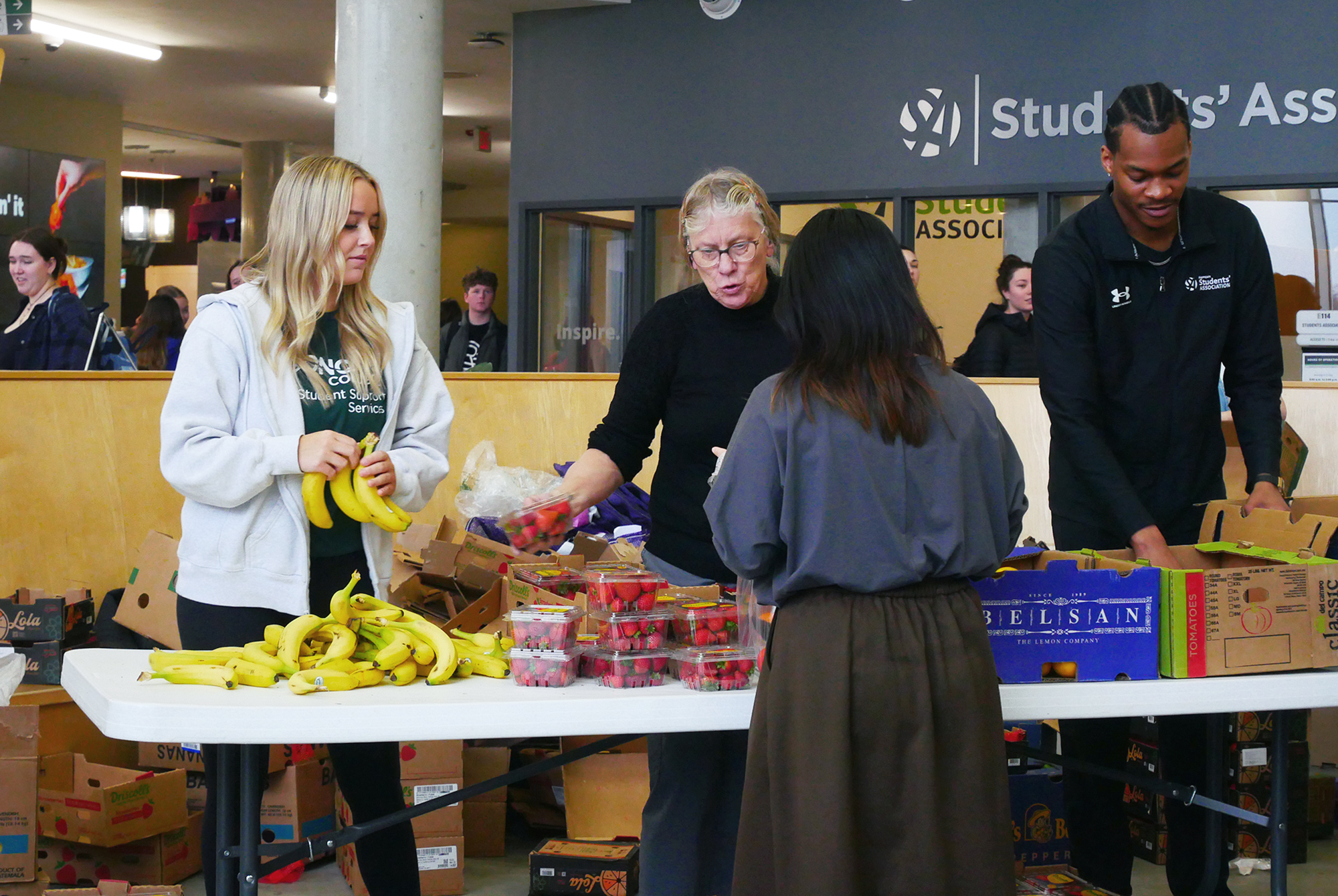 Starr Brommell (left), a business marketing student, Wilma Overbeek (middle) and Matteo Mongroo (right) giving food to the community.