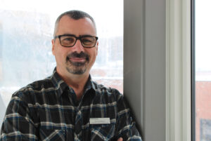 Alain Paradis, coordinator and professor of the graphic design program, smiling outside of his office in N-building on April 4.