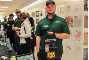 Daniel Mooney, a food service worker at the college, stands by the cybersecurity booth with the tote bag he won.