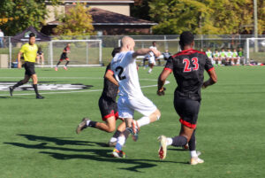 Algonquin's Oscar Forward (centre) about to kick a ball away from Fanshawe's Bilal El Said (left) and Ethan Gebremicael (right).