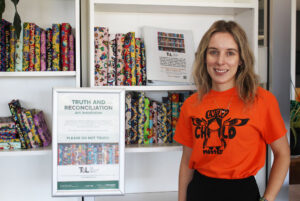 Lauren Laroque, special events coordinator, poses in front of wrapped books for Truth and Reconciliation Day.