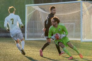 Algonquin's goalkeeper Olivier Langlois prepares to return an intercepted shot. Centre-back Kerim Tosun is behind him, while Humber forward Jacob Ball is on the left.