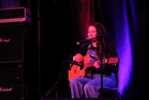 Monique Messier happily perfoming on stage with her guitar.