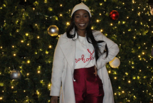 Marketing student Mercy Ejeye poses in front of the glowing Christmas tree