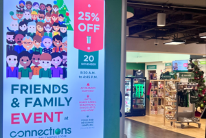 The entrance of the Connection store, featured a large digital sign announcing the start of the holiday event, with a display of arranged products.