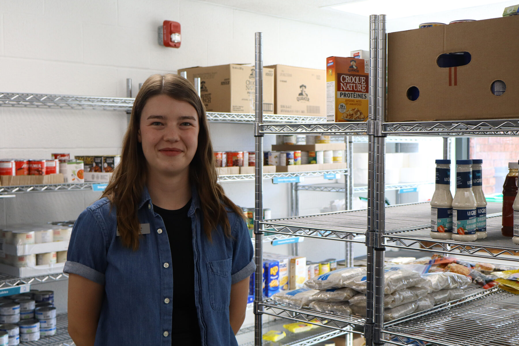 Abby Muir surrounded by food in the food cupboard in Room B102.