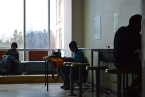 A still featuring three students using the common space in T building to work
