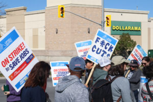 Full-time support staff at Algonquin College's Navaho entrance holding various signs.