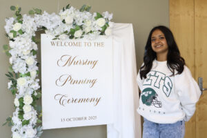 Anjali Chandel standing next to a sign she helped design that many graduating students were seen taking their own pictures next to before the ceremony.