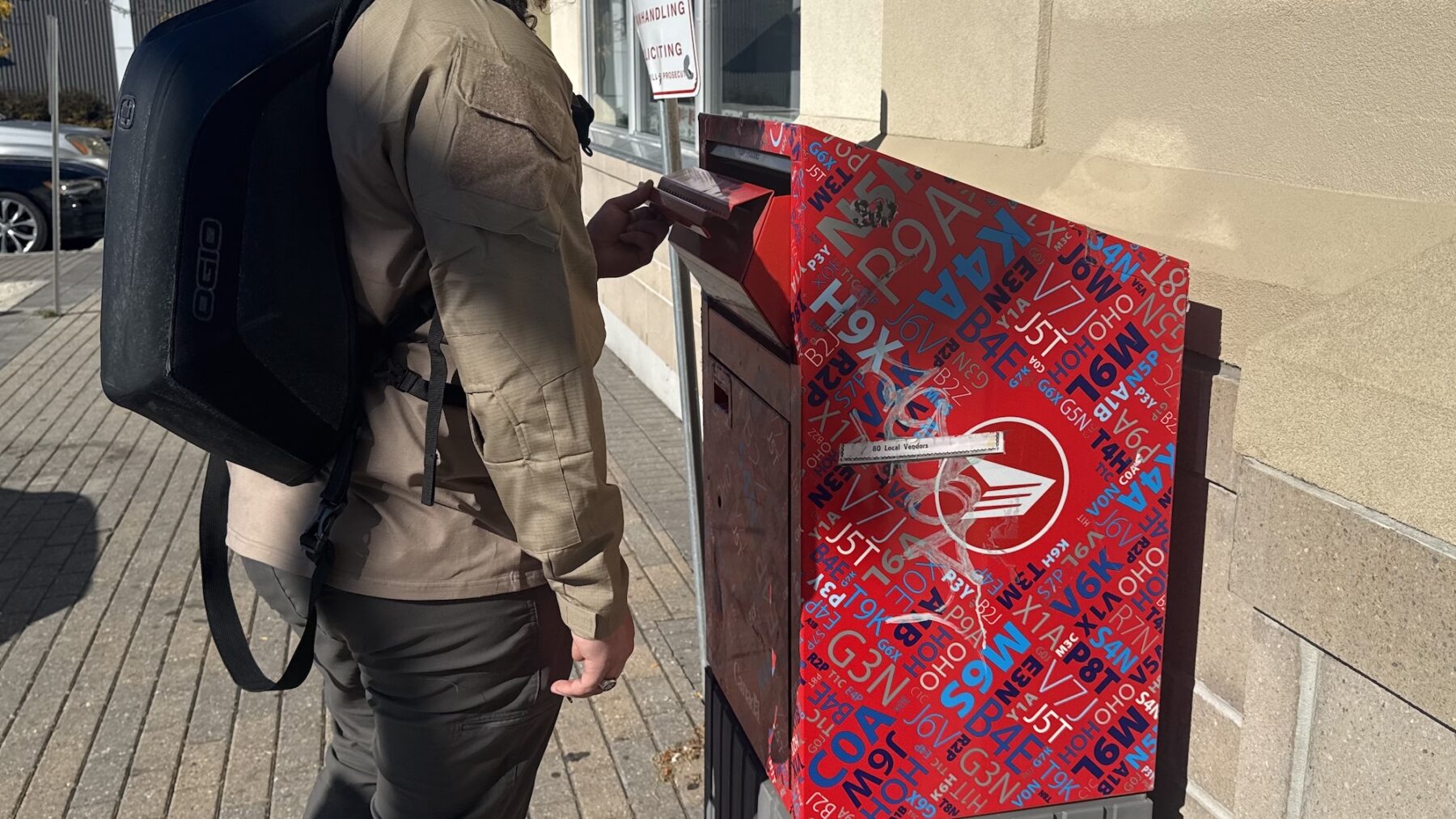 A student opening a Canada Post deposit box in College Square.