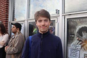 Chris Szabo standing outside the Mayfair Theatre in a blue sweater smiling at the camera