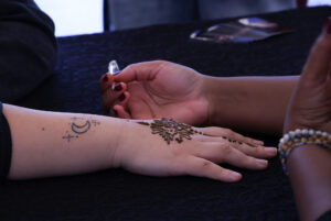 A student receives a henna tattoo by artist, Mumtaz Mohamoud (@designsbymumtaz).