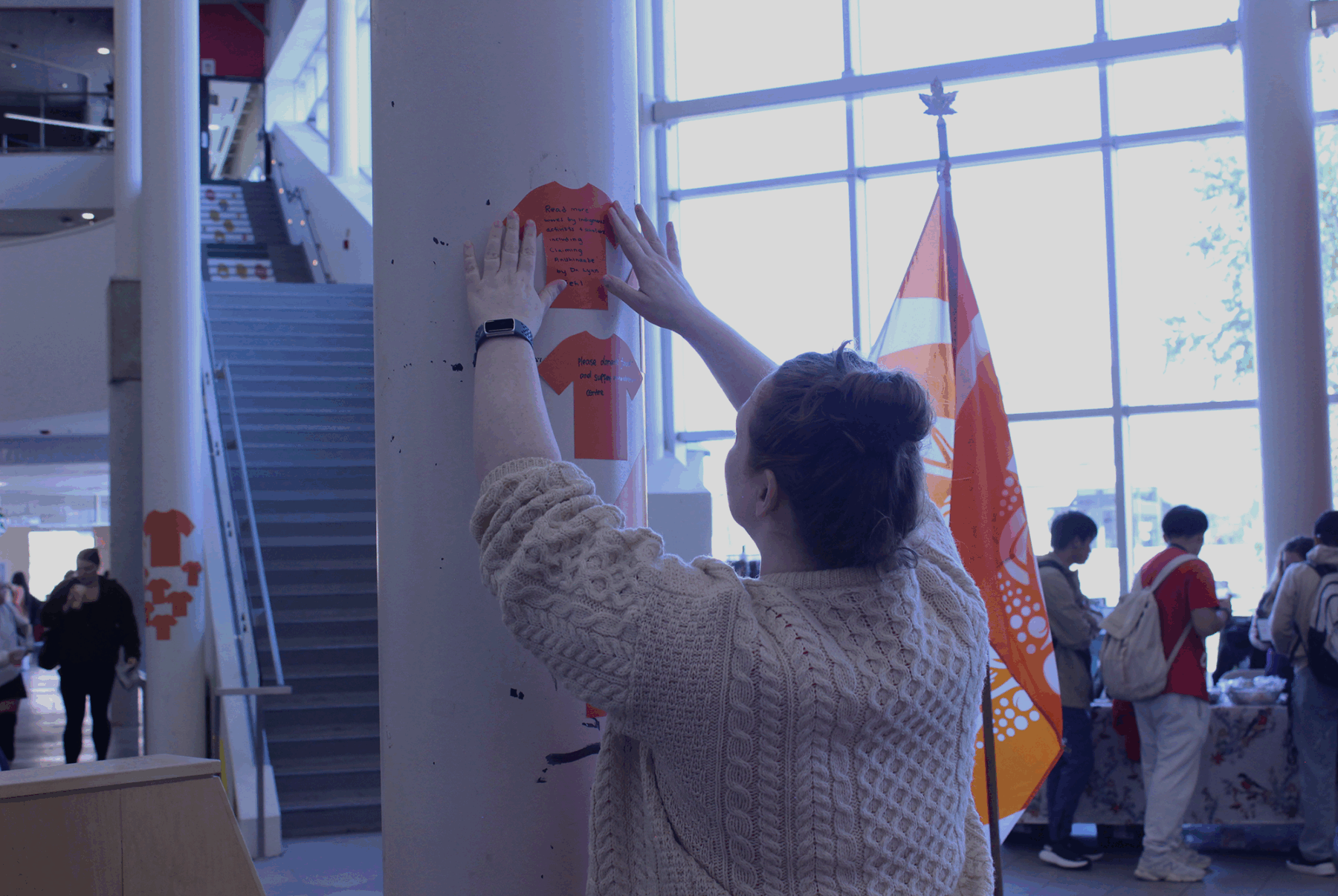 Niamh O’Shea hangs her orange paper shirt on one of the pillars on Sept. 30 in the Student Commons.