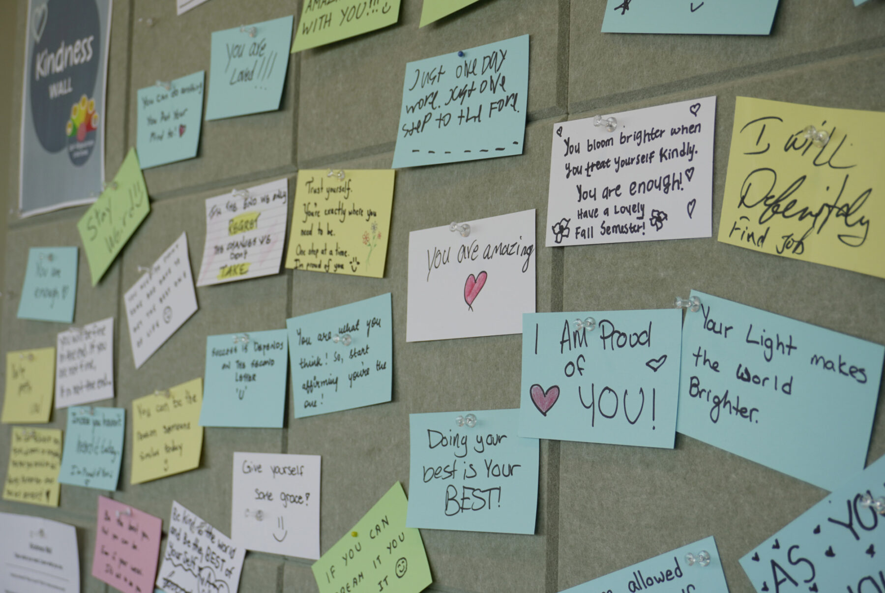Students write positive messages on sticky notes to support their peers on the Kindness Wall.
