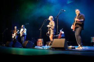 Members of Amos the Transparent playing instruments and singing on stage at Meridian Theatres at Centrepointe during Rock the Wild