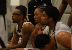 Algonquin Wolves men's basketball players, Shyeem Brown, Frank Thomas, and James Texeira, are listening in a timeout against the Centennial Colts.
